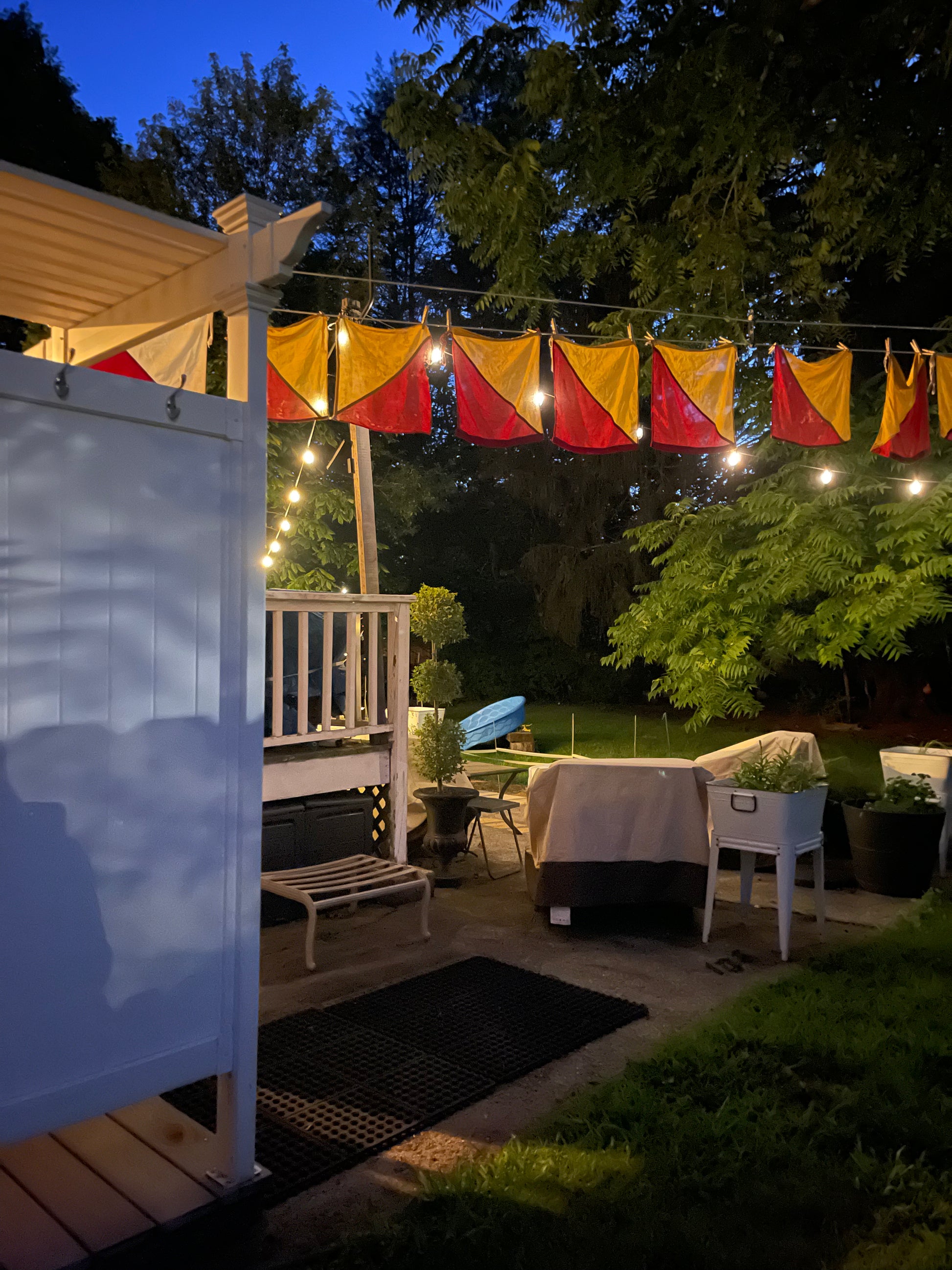 Backyard patio with colorful nautical signal flags, string lights, and outdoor furniture. Maritime decor.
